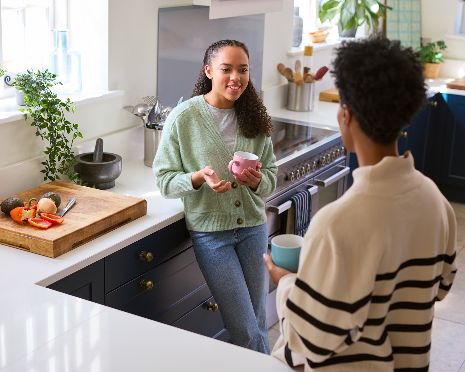 Parent and daughter talking in a kitchen.